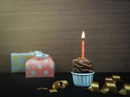 Sweet coffee chocolat cupcake with bow candle on wooden background with copy space. Happy birthday party background concept. photo