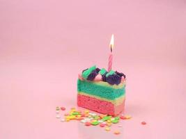 Happy birthday cake and bow candle on pink background with copy space. photo