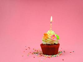 cupcake de feliz cumpleaños y vela de arco sobre fondo rosa con espacio para copiar, lindo pastel en la fiesta de cumpleaños. foto