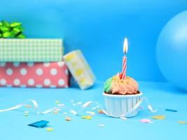 Sweet cupcake and bow candle on blue background with copy space. Happy birthday party photo