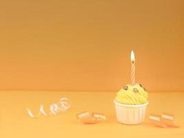 Sweet cupcake with bow candle on yellow background with copy space. Happy birthday party concept background. photo