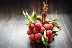 Fresh lychee fruits Litchi with leaves on wooden table photo