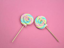 Colorful rainbow color meringue lollipop candy on pink background.  Cute summer sweet dessert concept. photo