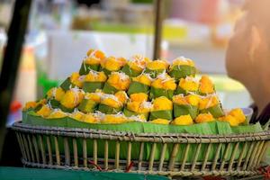 Kanom Tarn Thai name yellow toddy palm cake with  coconut slide in steaming pot. Thai dessert made from toddy palm fruit and packaging with banana leaf. photo