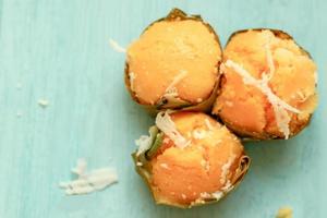 Kanom Tarn yellow toddy palm cake with  coconut slide, Thai dessert made from toddy palm fruit and packaging with banana leaf. Thai cupcake on blue background. photo