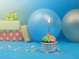 Sweet cupcake and bow candle on blue background with copy space. Happy birthday party photo