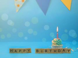 Sweet cupcake and bow candle on blue background with copy space. Happy birthday party photo