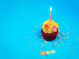 cupcake de feliz cumpleaños y vela de arco sobre fondo azul con espacio para copiar, lindo pastel en la fiesta de cumpleaños. foto