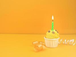 Sweet cupcake with bow candle on yellow background with copy space. Happy birthday party concept background. photo