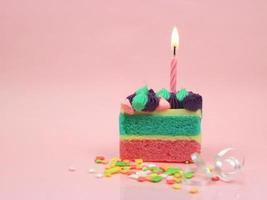 Happy birthday cake and bow candle on pink background with copy space. photo