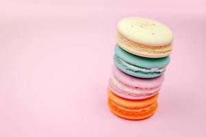 Colorful french macarons macaroons cake,  delicious sweet dessert on a pink background with copyspace, food background concept. photo