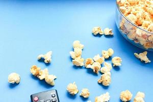Delicious caramel popcorns sweet dessert on blue background, snacks in a glass bowl for favorite movie times. photo