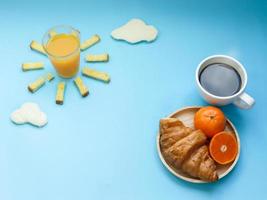 idea creativa de desayuno, cielo azul de la mañana del amanecer con comida en la nube, jugo de naranja, azúcar de mantequilla de pan crujiente, pan blanco nublado, croissant, café negro caliente y fruta de naranja. despierta en un día más brillante foto