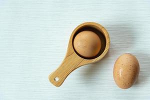 Raw fresh chicken eggs or boiled eggs in wooden spoon or boiled eggs in wooden spoon on isolated white gray line texture background photo