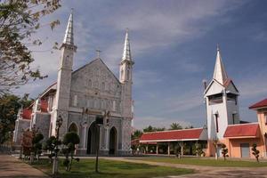 Ancient gray church and lawn at front with sky. photo