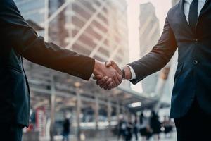 Businessman in suit handshake together for successful in city and walking people background. photo