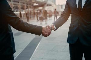 Businessman in suit handshake together for successful in city and walking people background. photo