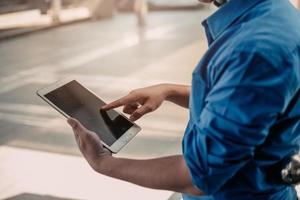 Close up. Men holding digital tablet and looking away while standing street with city in the background. photo