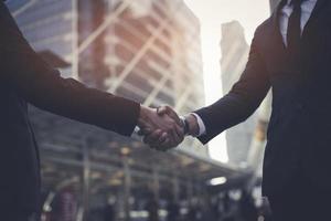 Businessman in suit handshake together for successful in city and walking people background. photo