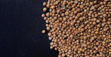 A spreaded dried coriander seed on black background. Ingredient background design. Available for text. Suitable for the food advertising of company and industry, poster, backdrop, flyer, etc. photo