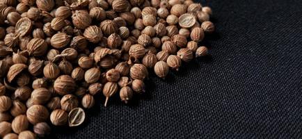 A spreaded dried coriander seed on black background. Ingredient background design. Available for text. Suitable for the food advertising of company and industry, poster, backdrop, flyer, etc. photo