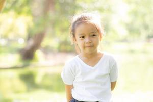 cara de retrato de linda niña asiática y felicidad y diversión infantil en el parque en verano, sonrisa y felicidad de niño asiático y relajación en el jardín, concepto de infancia de estilo de vida. foto