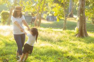 Young asian mother and little daughter playing the park with fun and happiness, family enjoy and relax and leisure together, mom and children smiling laughing in summer day. photo
