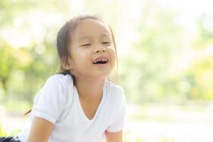 cara de retrato de linda niña asiática y felicidad y diversión infantil en el parque en verano, sonrisa y felicidad de niño asiático y relajación en el jardín, concepto de infancia de estilo de vida. foto