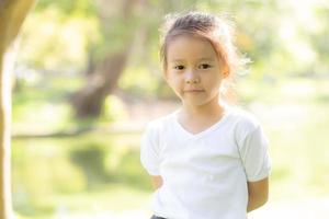 cara de retrato de linda niña asiática y felicidad y diversión infantil en el parque en verano, sonrisa y felicidad de niño asiático y relajación en el jardín, concepto de infancia de estilo de vida. foto