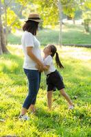 Young asian mother and little daughter playing the park with fun and happiness, family enjoy and relax and leisure together, mom and children smiling laughing in summer day. photo