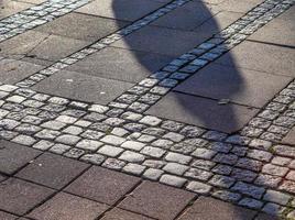 Shadows of people in a european shopping area on a cobblestone ground photo