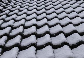 nieve blanca sobre tejas en invierno en una casa europea foto