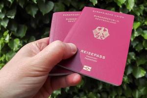 una mano masculina sostiene dos pasaportes alemanes para el control de pasaportes. foto