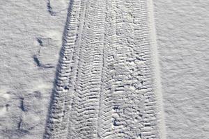 Tire Tracks on snow covered streets in a close up view. photo