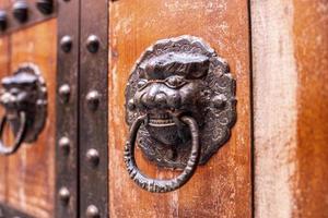 Detail of old metallic knocker or handle on the wooden door photo