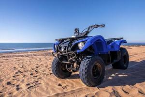 Quadbike de cuatro ruedas en la arena en la playa en un día soleado foto