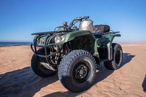 Quadbike de cuatro ruedas en la arena en la playa en un día soleado foto