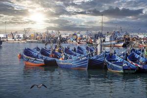 Wooden fishing boats anchored at marina against dramatic cloudy sky photo