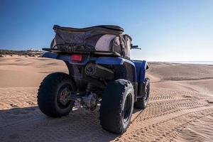 Four wheeler quadbike on sand at beach on bright sunny day photo