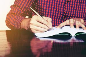 Young man hand writing on notebook with pen. photo