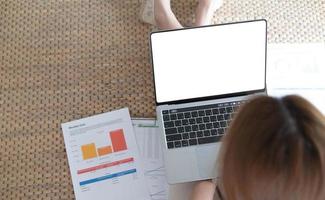 mujer que usa una computadora portátil con una pantalla vacía en blanco simulada escribiendo en una computadora en casa, pantalla de espacio de copia de maqueta para anuncios, búsqueda de empleo, estudio de compras en línea, página web, banca electrónica, vista sobre el hombro foto