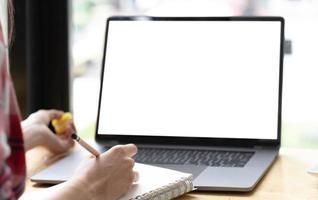 joven que trabaja en su computadora portátil con una pantalla de espacio en blanco para su mensaje de texto publicitario en la oficina, vista posterior de las manos del hombre de negocios ocupadas usando una computadora portátil en el escritorio de la oficina foto