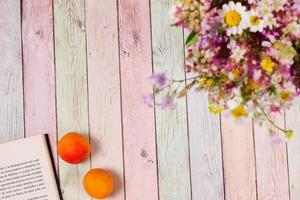 Apricots book and flowers on colorful table, copy space photo
