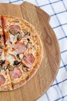 Pizza on a wooden tray and a blue checkered napkin. Foodphoto for pizzeria, menu, catalog, banner, leaflet photo