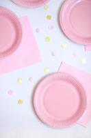 Pink paper disposable plates, napkins and straws for drinks on white background. Table setting for picnic. Bright eco-court. Birthday, party and holiday concept. Top view, flat lay photo