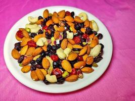 Las nueces y bayas sanas y nutritivas se colocan en un plato blanco sobre un fondo de color. foto