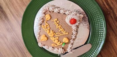 Birthday cake on a green plate on brown background. photo