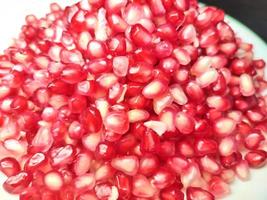 Pomegranate seeds placed on a white plate on a dark background photo