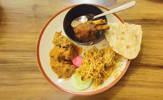 curry de pollo, curry de cordero, arroz y chapatti en plato blanco sobre fondo claro. foto