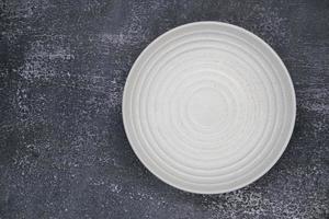 un plato vacío redondo blanco sobre fondo oscuro grunge para el concepto de alimentos e ingredientes configurado foto